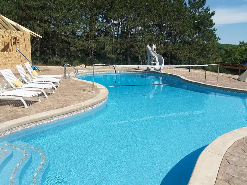 Lagoon-shaped pool with a sun shelf, loungers and a slide