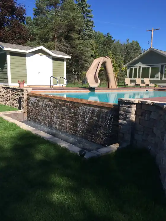A raised pool with a stone waterfall wall and a slide