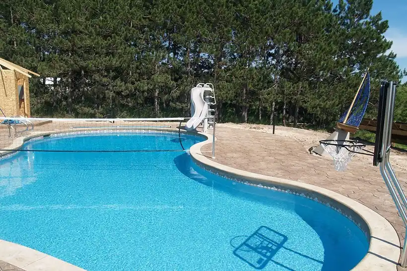 Free-form pool with a slide and a stamped concrete deck