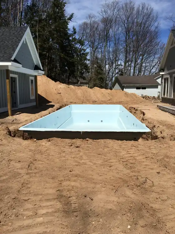 A fiberglass pool shell set in its excavation