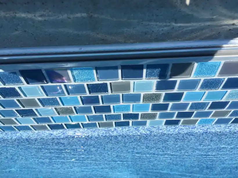 Close-up of mosaic tile along a pool waterline